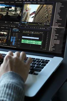 Male video programmer and editor sitting at computer working.